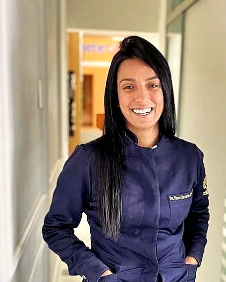 Dra. Vanessa Zangrandi sorrindo, de jaleco azul-marinho